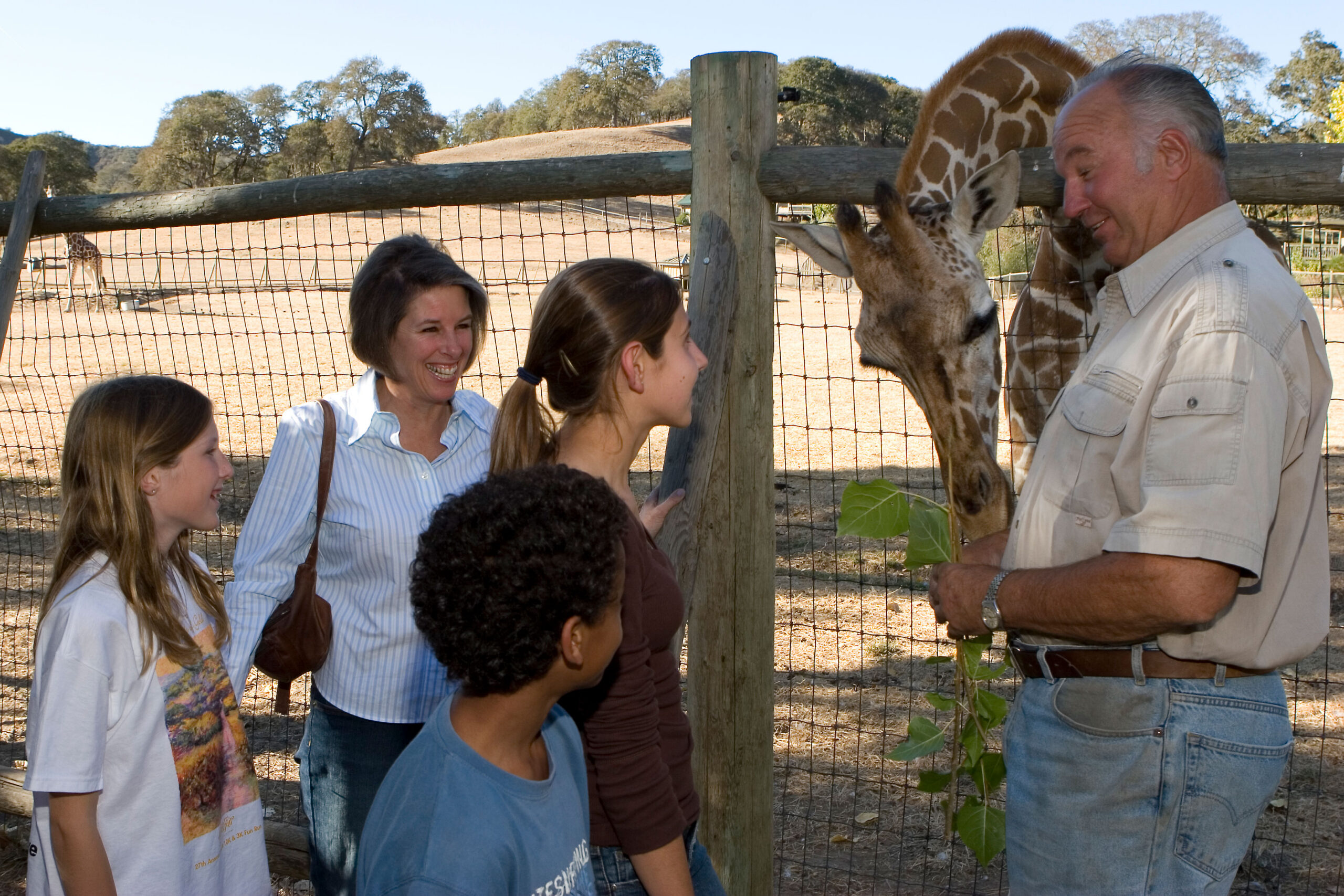 Peter and Nancy Lang doing a behind-the-scenes giraffe feeding with some kids